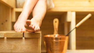 Frauenbeine und das Aufgussgefäß in einer Sauna (Quelle: colourbox)